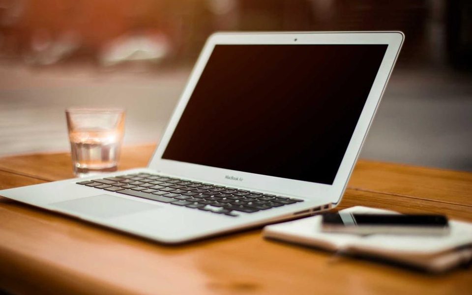 Ein aufgeräumter Schreibtisch mit einem offenen Laptop